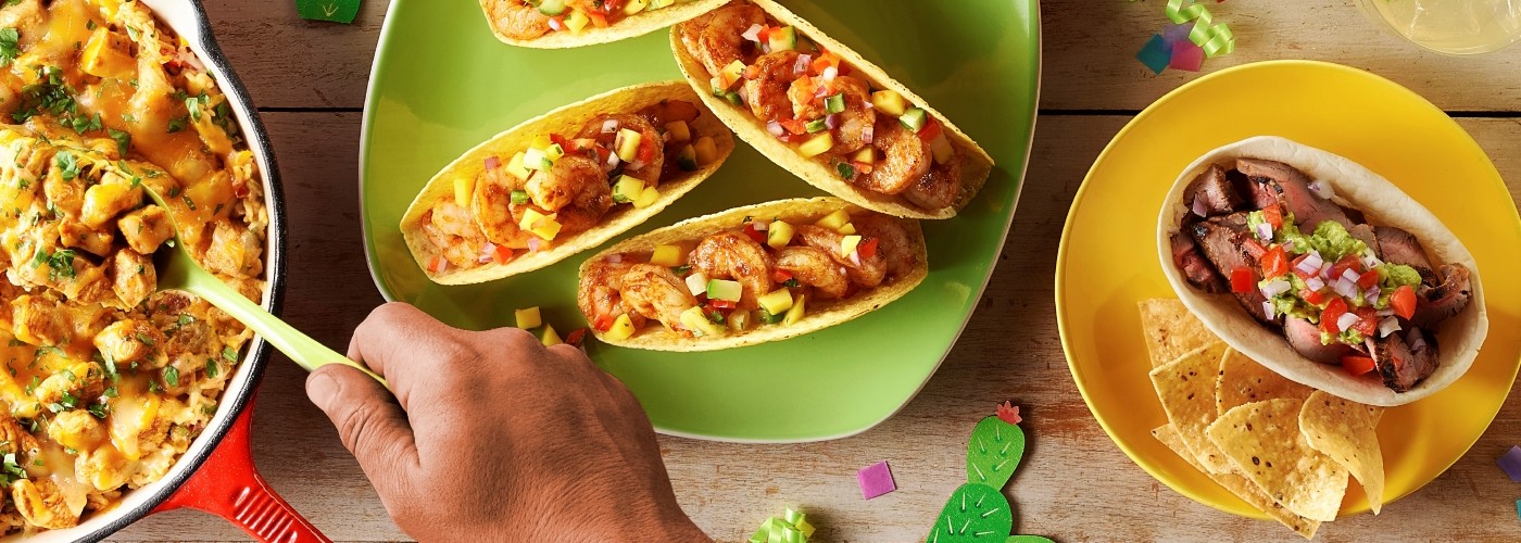 Colorful gluten-free tacos and a chicken casserole served on a wooden table