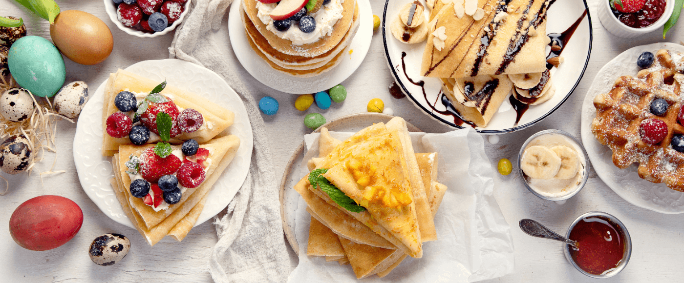 a variety of crepes, waffles and pancakes with fruits, chocolate drizzle & syrup alongside Easter eggs & toppings