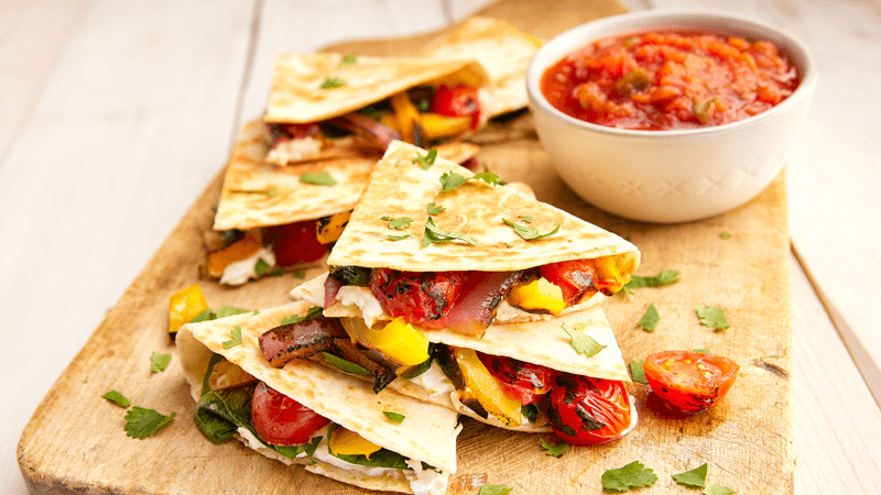 Charred Veggie Quesadillas with Goat Cheese served  on wooden plate with salsa